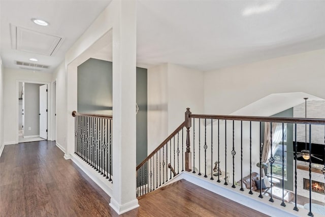 corridor with wood finished floors, an upstairs landing, visible vents, and baseboards