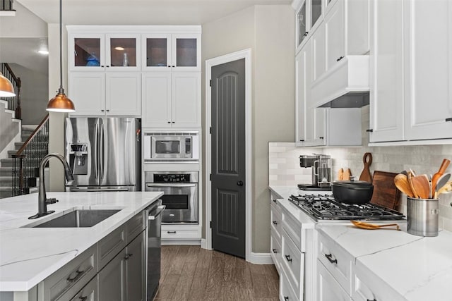 kitchen featuring a sink, backsplash, custom range hood, stainless steel appliances, and dark wood-style flooring