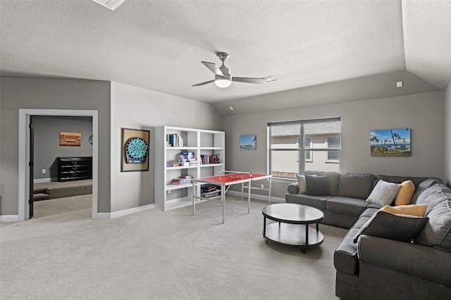 carpeted living area featuring a textured ceiling, baseboards, a ceiling fan, and vaulted ceiling