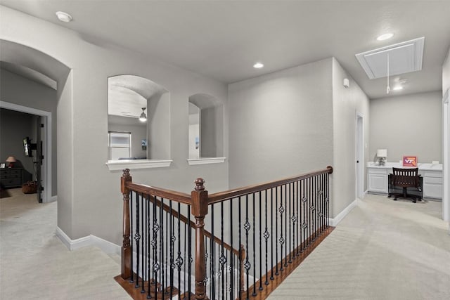 hallway with baseboards, light carpet, attic access, and an upstairs landing