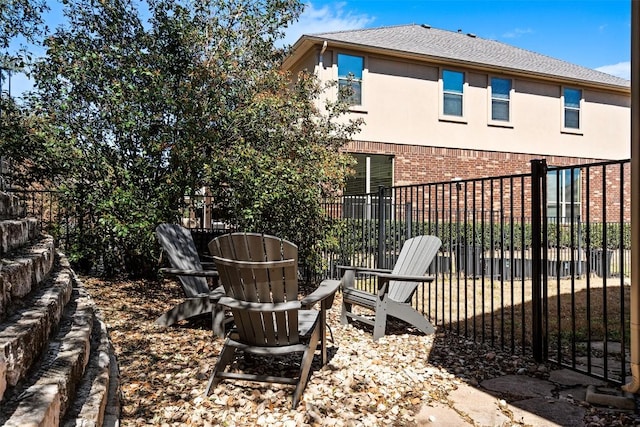 rear view of property featuring stucco siding, brick siding, roof with shingles, and fence