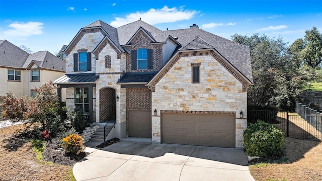 french country style house featuring fence, driveway, roof with shingles, a standing seam roof, and metal roof