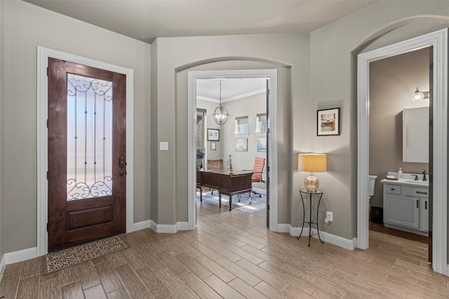 entryway featuring light wood-type flooring, baseboards, and a chandelier