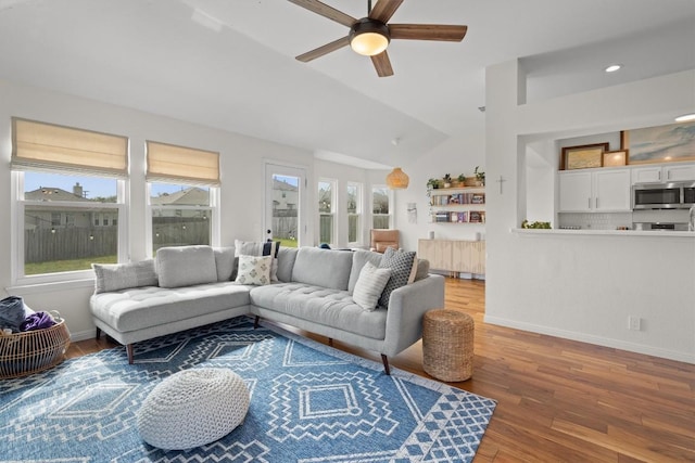 living room featuring ceiling fan, lofted ceiling, wood finished floors, and baseboards