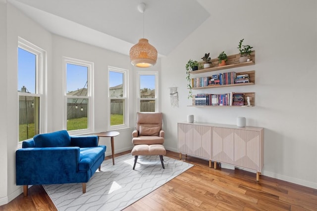 living area featuring light wood-style flooring, radiator heating unit, baseboards, and vaulted ceiling