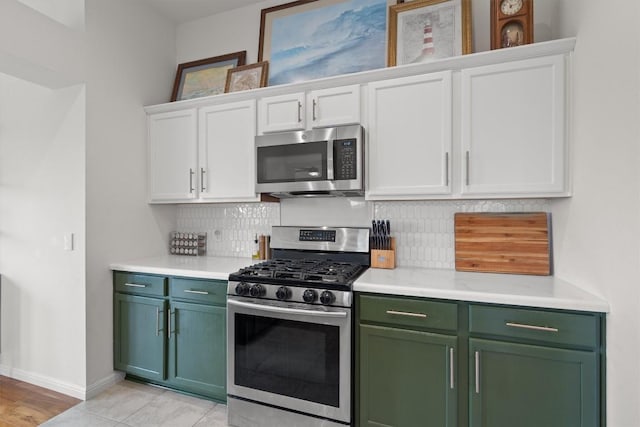 kitchen with tasteful backsplash, appliances with stainless steel finishes, green cabinets, and white cabinets