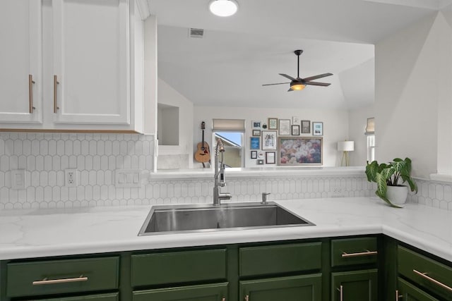 kitchen featuring visible vents, backsplash, green cabinetry, white cabinetry, and a sink