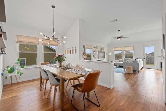 dining space featuring vaulted ceiling, ceiling fan with notable chandelier, baseboards, and wood finished floors