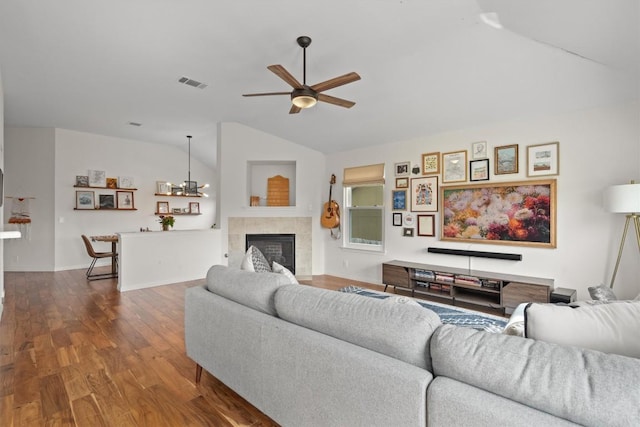 living room with dark wood finished floors, visible vents, lofted ceiling, ceiling fan, and a fireplace