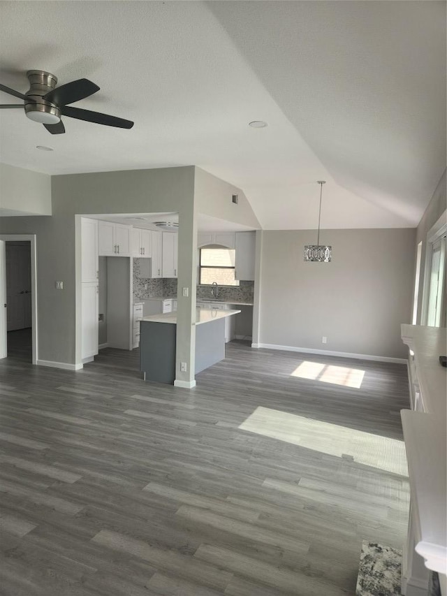 unfurnished living room featuring lofted ceiling, a ceiling fan, dark wood-style flooring, and a sink