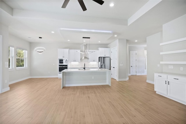 kitchen featuring tasteful backsplash, pendant lighting, light wood-type flooring, stainless steel appliances, and a sink