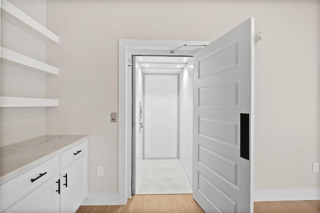 corridor with baseboards and light wood-style floors