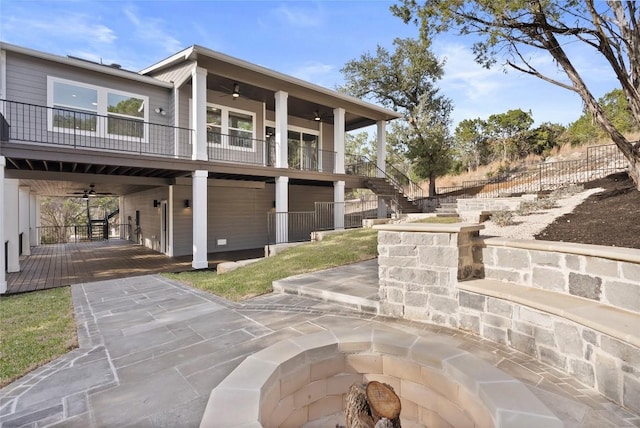 view of side of home featuring stairway, a balcony, a ceiling fan, and fence