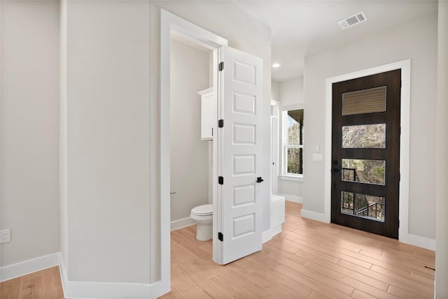 corridor featuring visible vents, light wood-type flooring, and baseboards