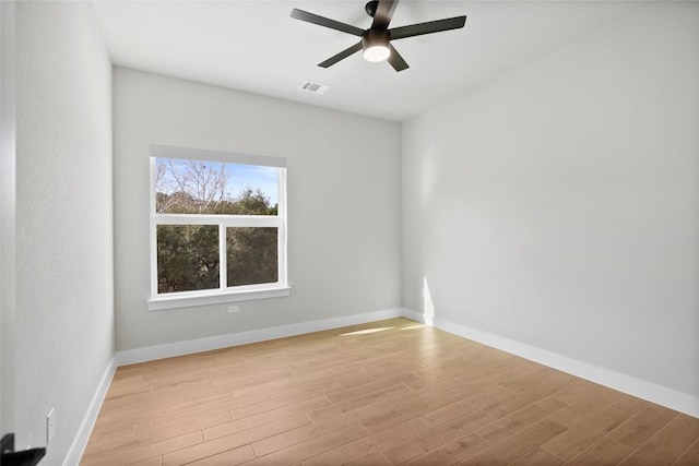 spare room featuring light wood finished floors, visible vents, a ceiling fan, and baseboards