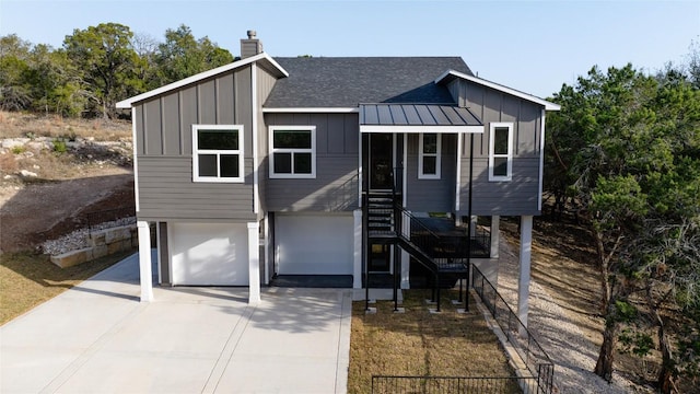 view of front of house featuring board and batten siding, a shingled roof, stairway, a chimney, and driveway