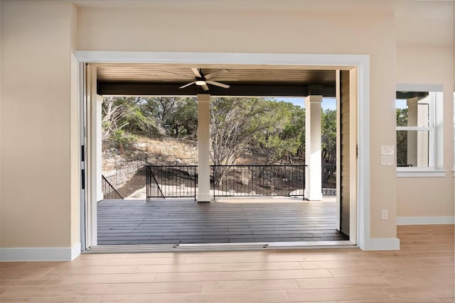 doorway featuring baseboards, wood finished floors, and a ceiling fan