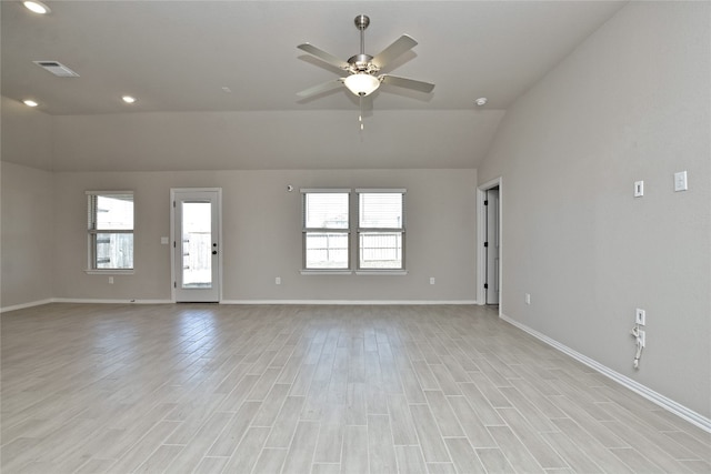 unfurnished room with a wealth of natural light, light wood-type flooring, baseboards, and vaulted ceiling