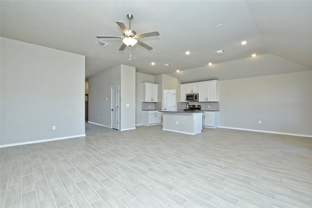 unfurnished living room with visible vents, baseboards, ceiling fan, and vaulted ceiling