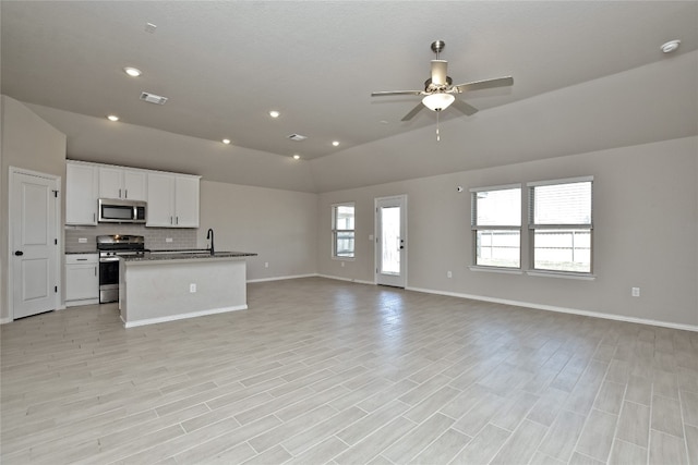 kitchen featuring open floor plan, white cabinets, stainless steel appliances, a ceiling fan, and a sink