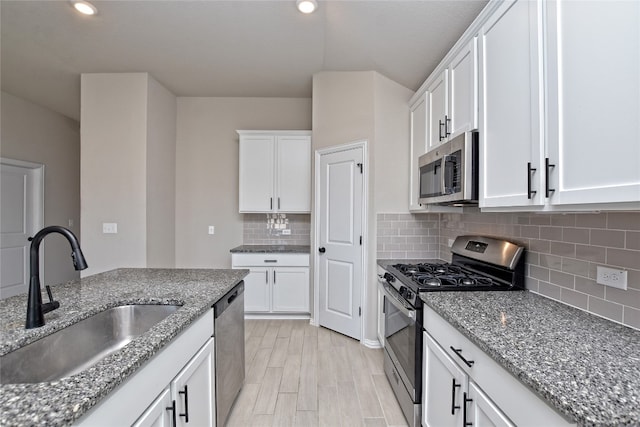 kitchen featuring white cabinets, stone countertops, appliances with stainless steel finishes, and a sink