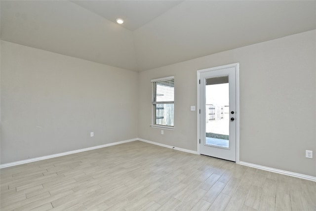 spare room featuring baseboards, vaulted ceiling, and light wood finished floors