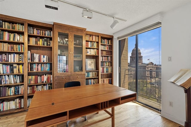 home office with rail lighting, a textured ceiling, and wood finished floors