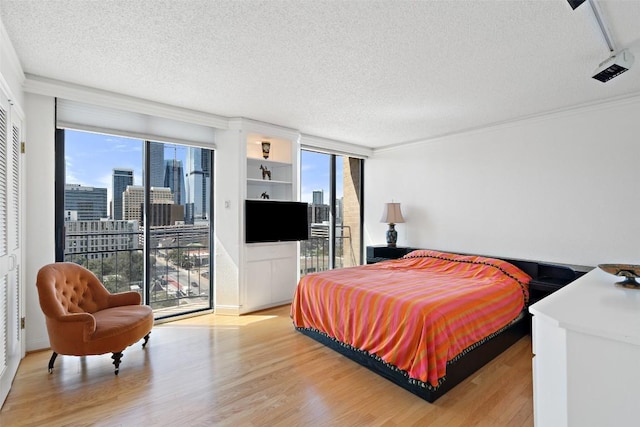 bedroom with access to exterior, a textured ceiling, and light wood-style floors