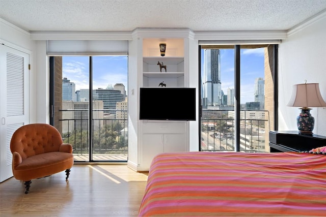 bedroom featuring crown molding, access to outside, wood finished floors, and a textured ceiling