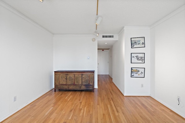 unfurnished room featuring baseboards, visible vents, track lighting, crown molding, and light wood-type flooring