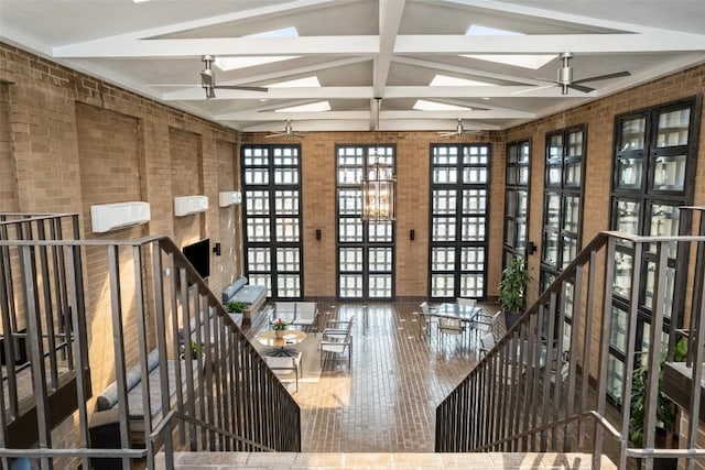 interior space featuring beam ceiling, brick wall, high vaulted ceiling, and a ceiling fan