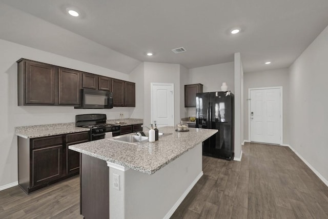 kitchen featuring visible vents, an island with sink, dark wood-style flooring, black appliances, and dark brown cabinets