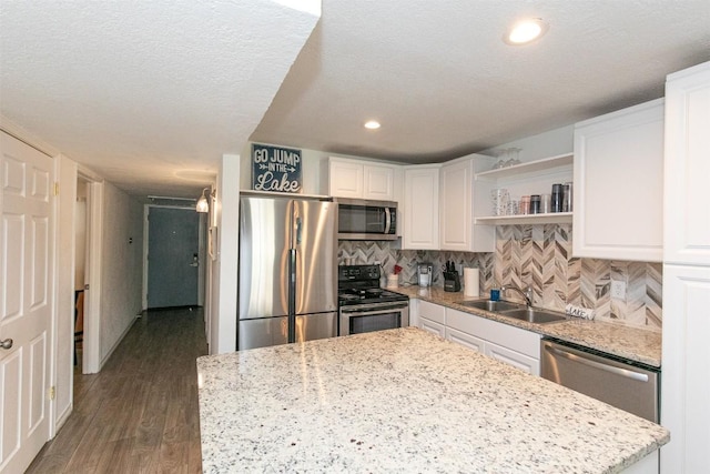 kitchen featuring open shelves, dark wood-style flooring, a sink, white cabinets, and appliances with stainless steel finishes