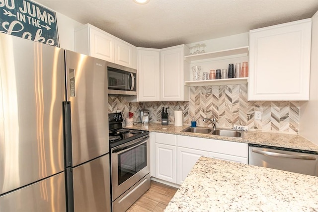 kitchen featuring a sink, open shelves, tasteful backsplash, white cabinetry, and appliances with stainless steel finishes