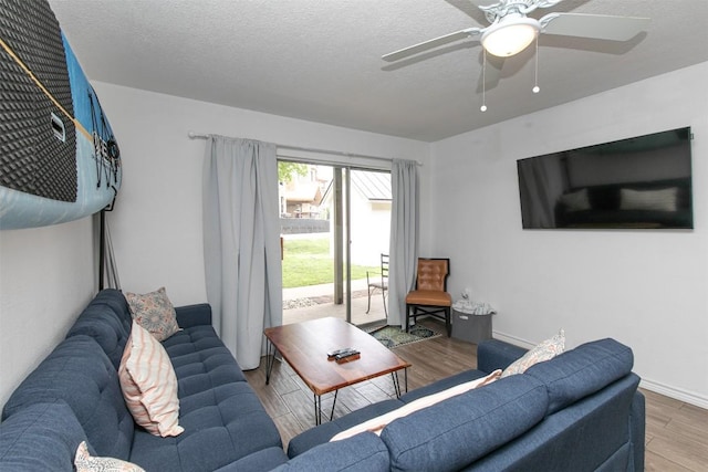 living area featuring ceiling fan, baseboards, a textured ceiling, and wood finished floors