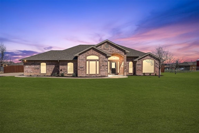 french country inspired facade featuring a front yard, fence, and roof with shingles