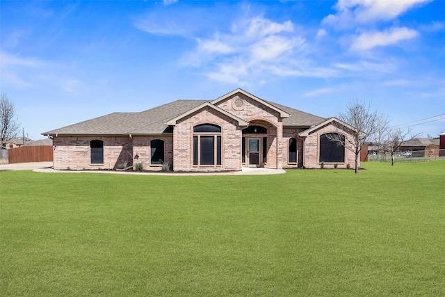 view of front of home with brick siding, a shingled roof, and a front lawn