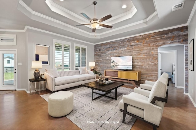 living area featuring arched walkways, concrete flooring, and a tray ceiling