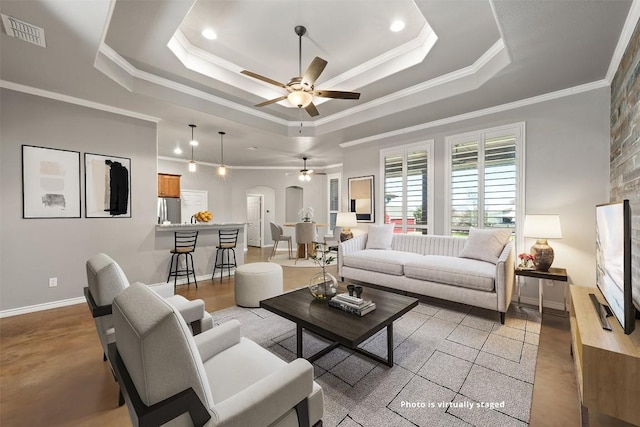 living room with a tray ceiling, arched walkways, visible vents, and ornamental molding