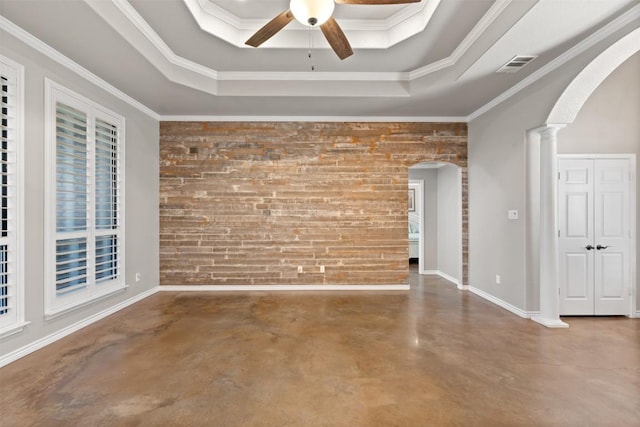 empty room with a ceiling fan, a tray ceiling, visible vents, and arched walkways