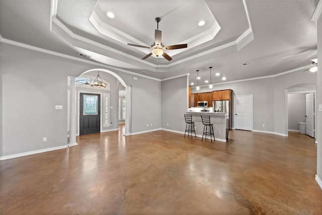 unfurnished living room featuring a tray ceiling, arched walkways, and ceiling fan with notable chandelier