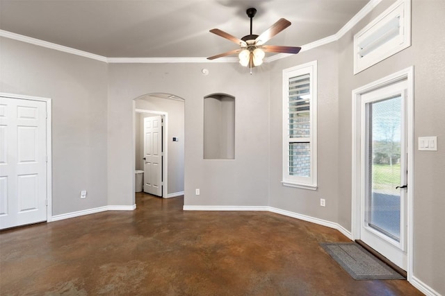 spare room with baseboards, arched walkways, ceiling fan, ornamental molding, and finished concrete floors