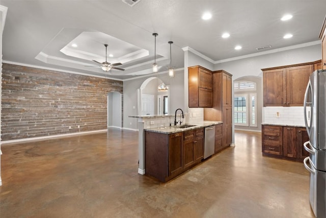 kitchen with a tray ceiling, arched walkways, appliances with stainless steel finishes, and finished concrete flooring