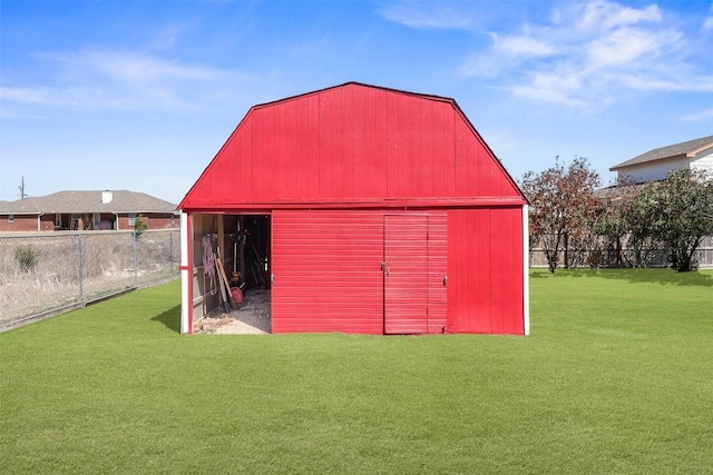 view of barn featuring a lawn and fence