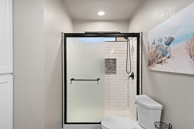 full bathroom featuring toilet, a stall shower, and a textured wall