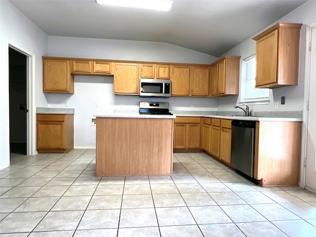 kitchen with light tile patterned floors, appliances with stainless steel finishes, a kitchen island, and a sink