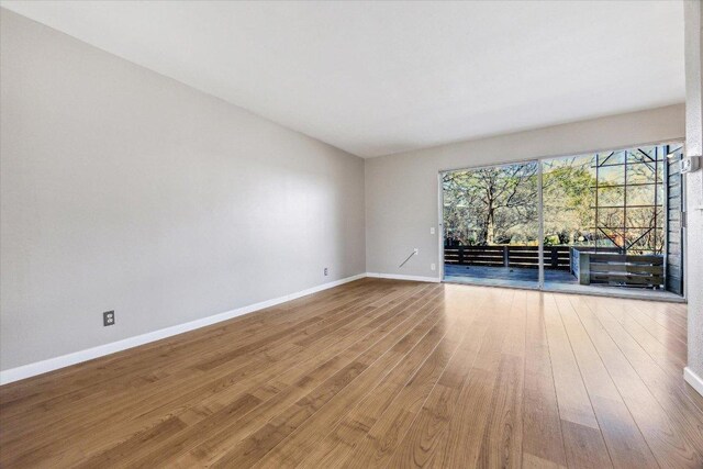 spare room featuring baseboards and wood finished floors