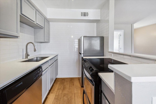 kitchen with visible vents, dishwasher, light wood-style flooring, range with electric stovetop, and a sink