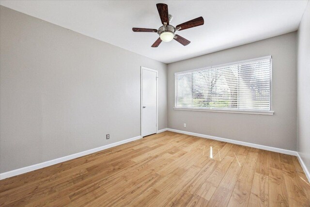 empty room featuring a ceiling fan, light wood-type flooring, and baseboards