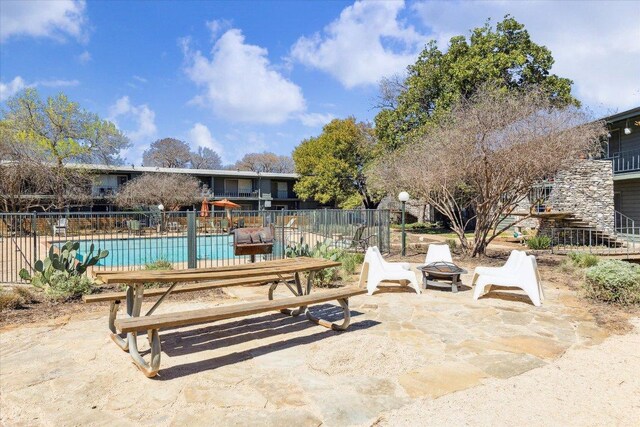 view of patio featuring a community pool, a fire pit, and fence